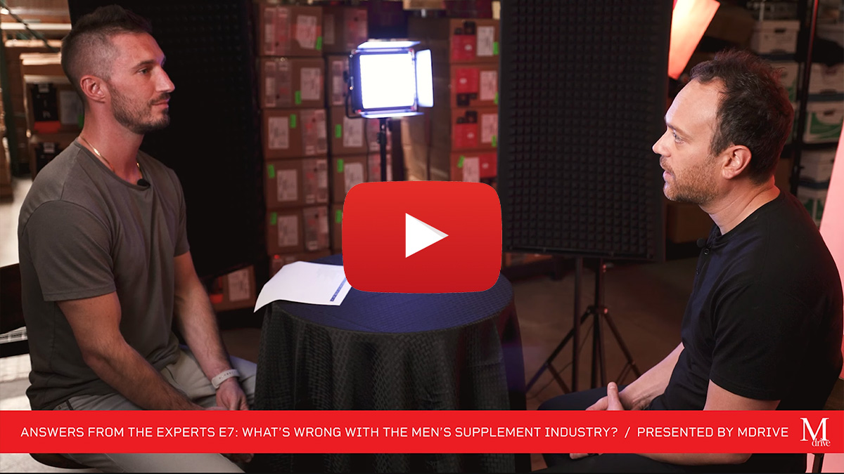 Still of video showing 2 men discussing supplements in a staged warehouse